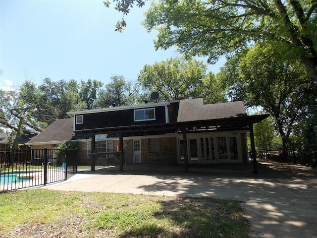back of house with a patio, a carport, stone siding, and fence