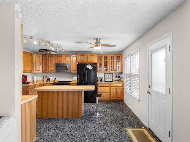 kitchen with a center island, light countertops, a textured ceiling, visible vents, and appliances with stainless steel finishes