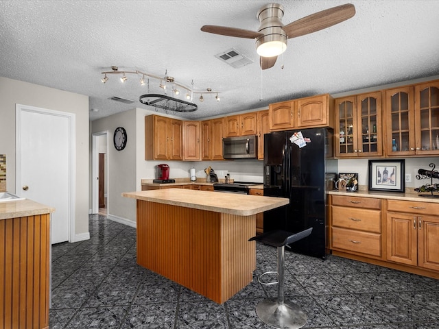 kitchen with stainless steel appliances, glass insert cabinets, visible vents, and light countertops