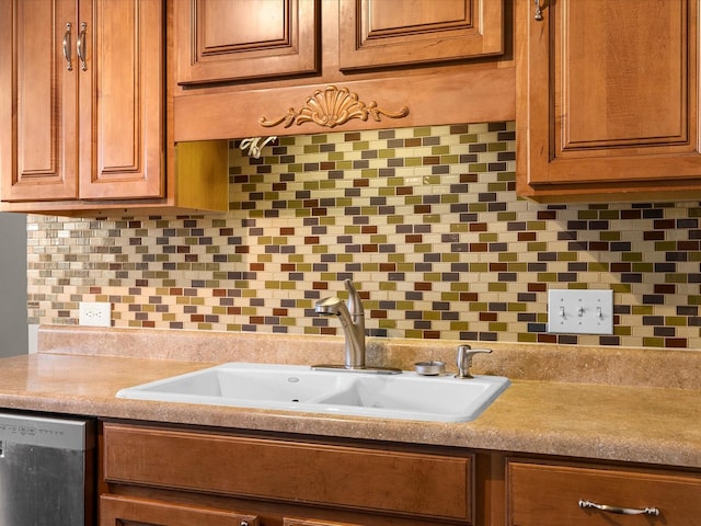 kitchen featuring stainless steel dishwasher, brown cabinetry, tasteful backsplash, a sink, and light countertops
