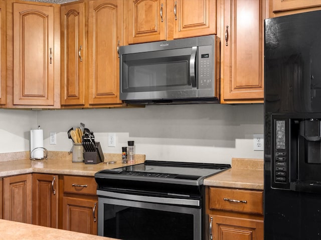 kitchen with brown cabinets, light countertops, refrigerator with ice dispenser, and stainless steel electric range