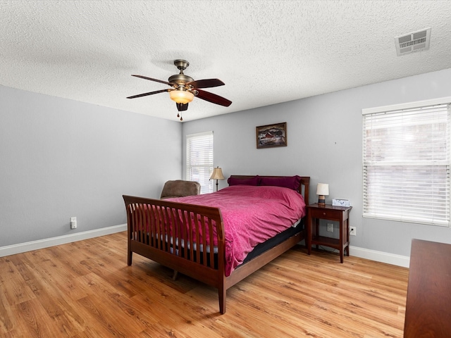 bedroom featuring visible vents, light wood-type flooring, and a textured ceiling