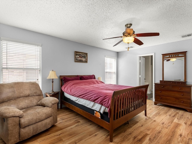 bedroom with a textured ceiling, ceiling fan, visible vents, and light wood-type flooring