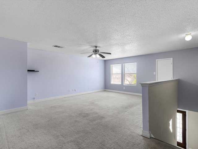 spare room featuring visible vents, ceiling fan, carpet flooring, and a textured ceiling