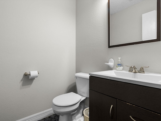 half bath with toilet, vanity, and baseboards