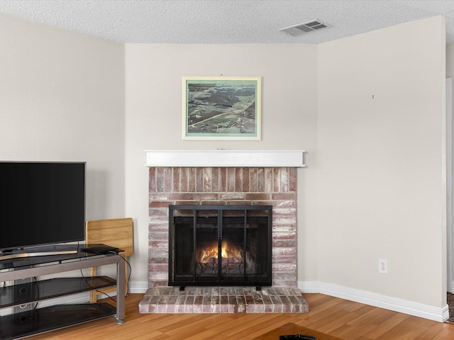 details with visible vents, a brick fireplace, wood finished floors, and baseboards