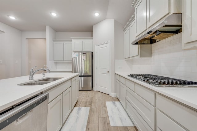 kitchen featuring stainless steel appliances, light countertops, under cabinet range hood, and a sink