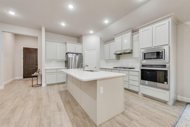 kitchen with under cabinet range hood, backsplash, light countertops, a sink, and appliances with stainless steel finishes