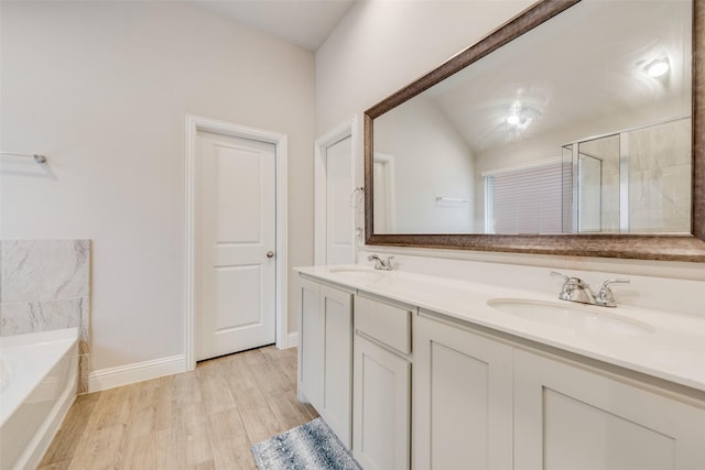 full bathroom featuring a garden tub, wood finished floors, a sink, and double vanity