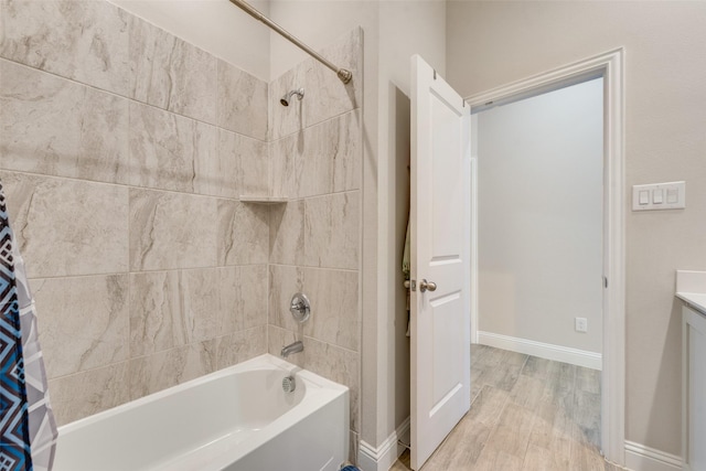 full bathroom with wood finished floors, shower / bath combo with shower curtain, baseboards, and vanity