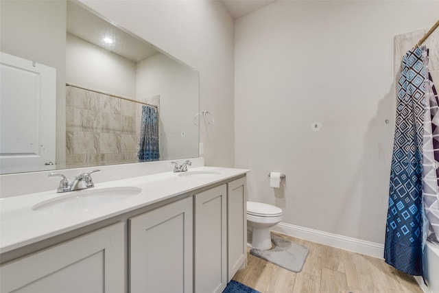 bathroom with wood finished floors, a sink, double vanity, and toilet