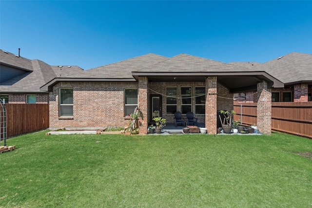rear view of property with a patio, a yard, a fenced backyard, and brick siding
