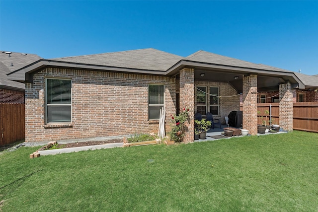 back of property featuring a lawn, fence, a patio, and brick siding
