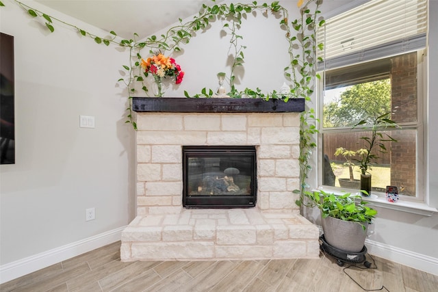 room details featuring wood finished floors, baseboards, and a stone fireplace