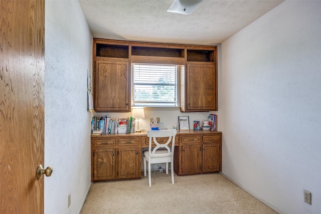home office with a textured ceiling, a textured wall, and light carpet