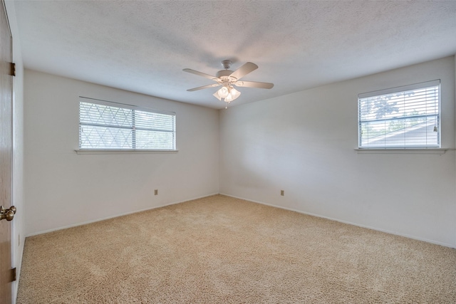 carpeted spare room with baseboards, a wealth of natural light, and ceiling fan