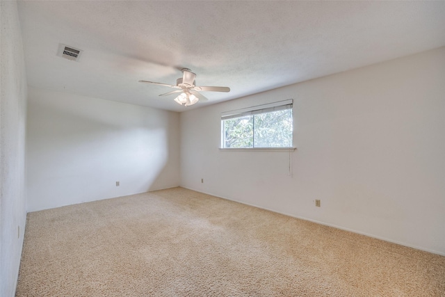 spare room with visible vents, ceiling fan, and carpet