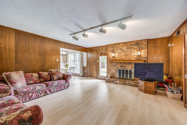 living area with rail lighting, wood finished floors, wood walls, and a fireplace