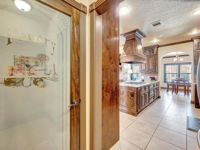 194 Royal Pnes, Lufkin, TX 75904 - kitchen featuring arched walkways, light tile patterned floors, tasteful backsplash, custom exhaust hood, and stainless steel gas stovetop