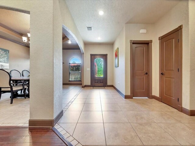 194 Royal Pnes, Lufkin, TX 75904 - foyer featuring a textured ceiling, arched walkways, a textured wall, tile patterned flooring, and baseboards