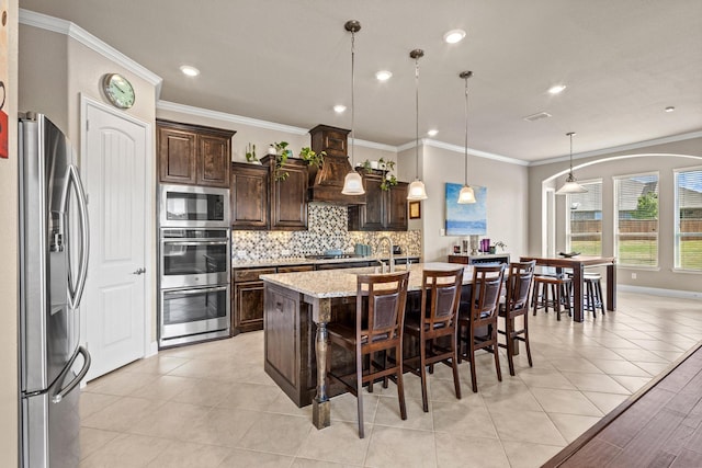 4304 Caney Creek Cir, Celina, TX 75078 - kitchen with tasteful backsplash, dark brown cabinetry, a breakfast bar area, stainless steel appliances, and custom range hood
