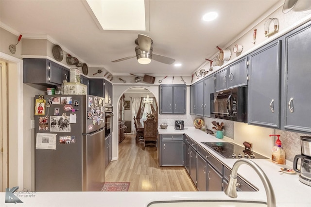 kitchen with arched walkways, light countertops, ceiling fan, black appliances, and light wood-style flooring