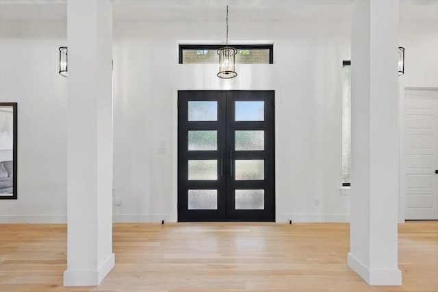 foyer featuring baseboards, wood finished floors, and a healthy amount of sunlight