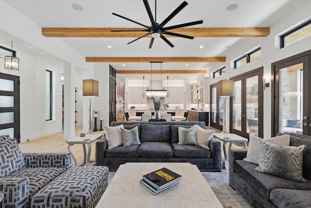 living area with light wood-style floors, ceiling fan with notable chandelier, beamed ceiling, and recessed lighting