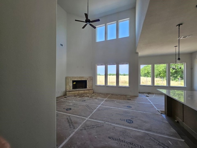213 Pilot Dr, Caddo Mills, TX 75135 - unfurnished living room with a fireplace with raised hearth, a towering ceiling, and ceiling fan