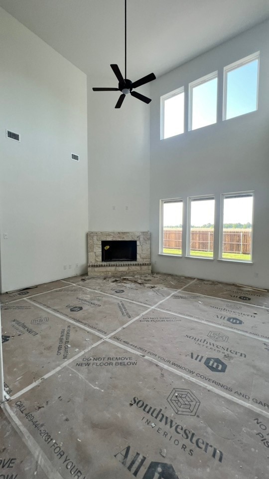 213 Pilot Dr, Caddo Mills, TX 75135 - unfurnished living room featuring a ceiling fan, a towering ceiling, and a stone fireplace