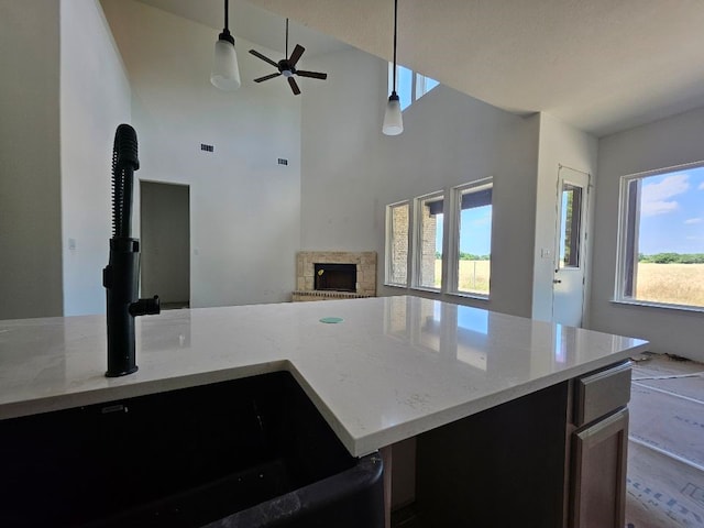 213 Pilot Dr, Caddo Mills, TX 75135 - kitchen featuring open floor plan, a sink, a ceiling fan, a fireplace, and light stone countertops