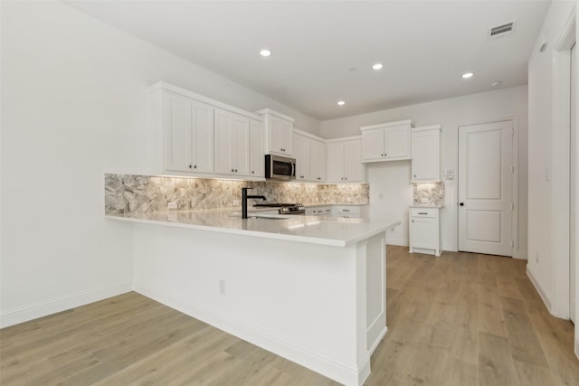 15712 Millwood Trl, Frisco, TX 75033 - kitchen featuring a peninsula, light wood-style floors, stainless steel appliances, and light countertops