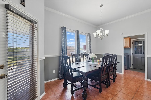 dining space featuring light tile patterned floors, washer / clothes dryer, ornamental molding, a notable chandelier, and baseboards