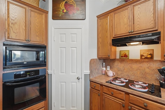 kitchen featuring brown cabinetry, under cabinet range hood, black appliances, and decorative backsplash