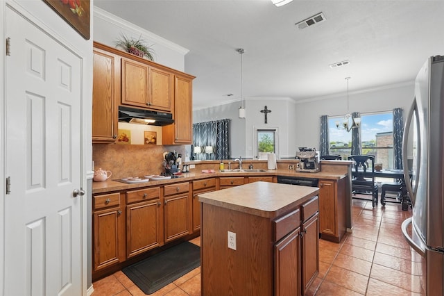 kitchen with freestanding refrigerator, a peninsula, visible vents, under cabinet range hood, and a sink