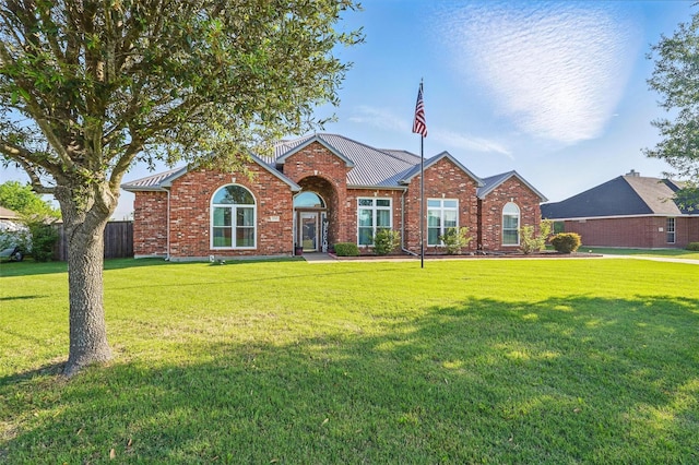 single story home with metal roof, a front lawn, and brick siding