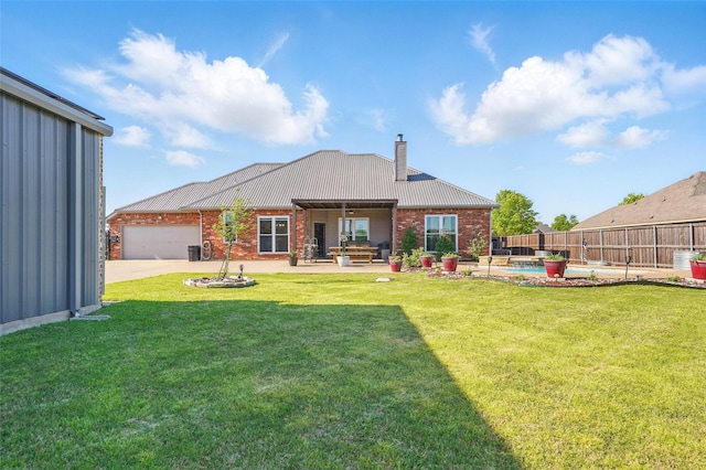 rear view of house with a patio area, a garage, a lawn, a chimney, and fence