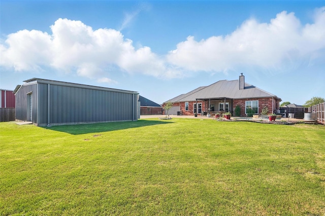 view of yard featuring a patio, fence, an outbuilding, and a pole building