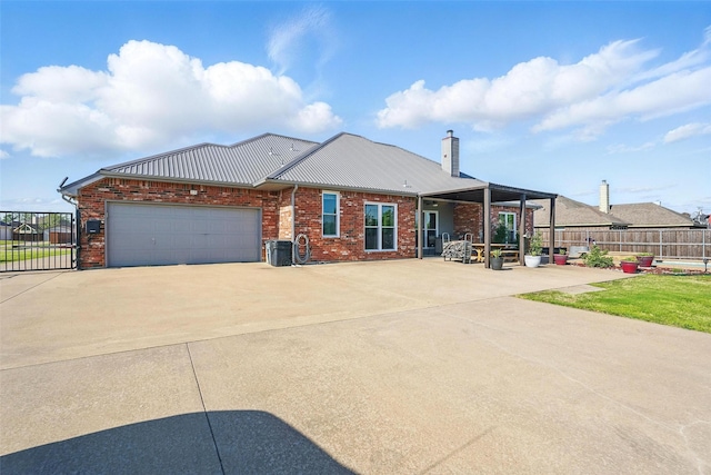 view of front of home featuring an attached garage, metal roof, fence, brick siding, and driveway