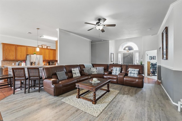 living room with light wood finished floors, baseboards, a ceiling fan, and crown molding