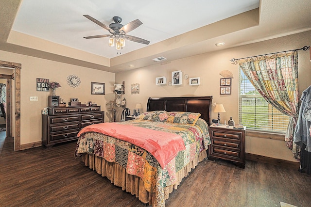 bedroom featuring recessed lighting, a tray ceiling, visible vents, dark wood-type flooring, and baseboards