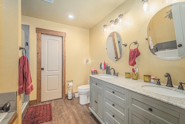full bathroom with wood finished floors, toilet, a stall shower, and a sink