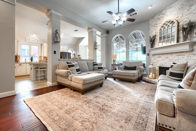3419 Willowcreek Dr, Sunnyvale, TX 75182 - living room with a fireplace, ceiling fan, decorative columns, visible vents, and dark wood finished floors