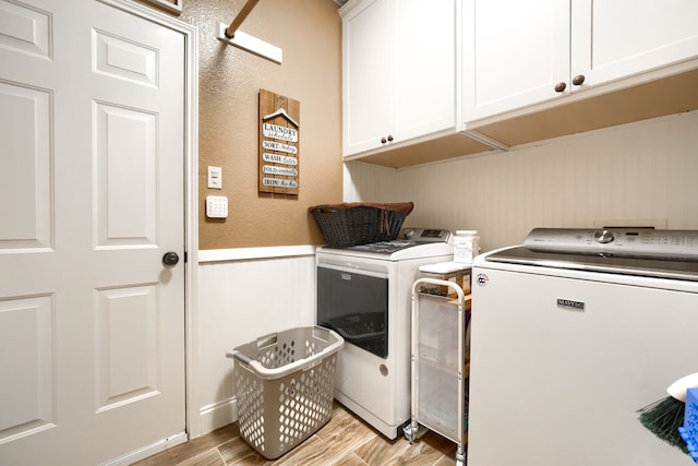 3419 Willowcreek Dr, Sunnyvale, TX 75182 - laundry area featuring light wood-type flooring, washer and clothes dryer, cabinet space, a decorative wall, and wainscoting