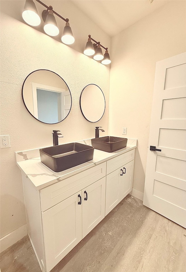 full bathroom featuring double vanity, baseboards, and a sink