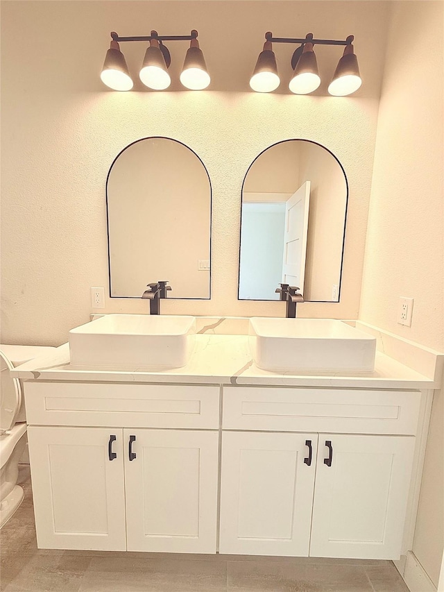 bathroom featuring toilet, double vanity, and a sink