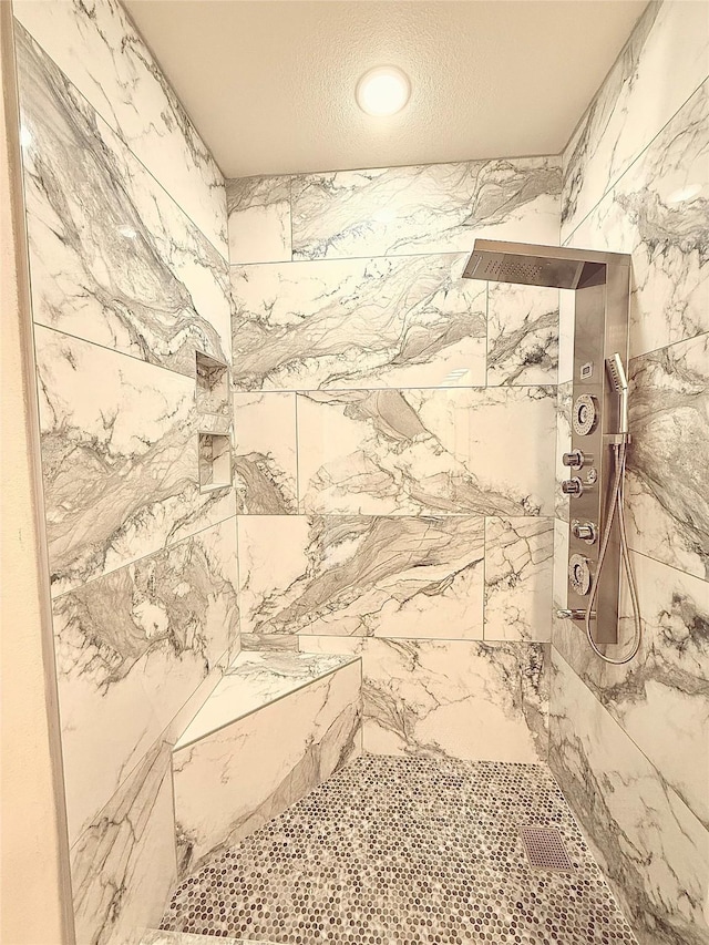 full bath with a tile shower and a textured ceiling