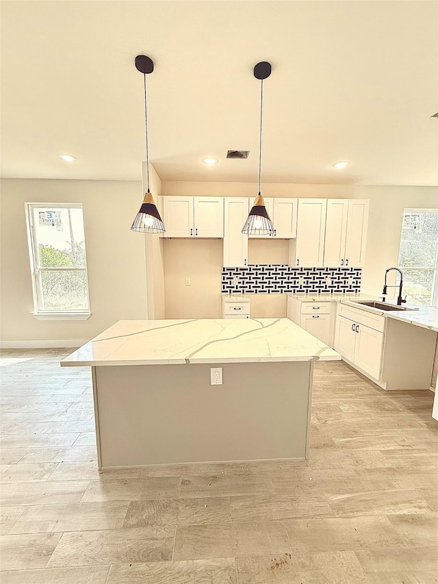 kitchen featuring a sink, pendant lighting, recessed lighting, and light stone counters