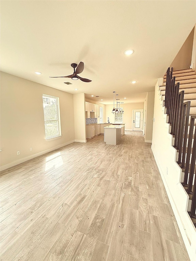 unfurnished living room with recessed lighting, stairway, light wood-type flooring, and ceiling fan
