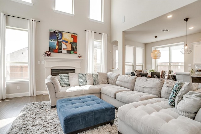 621 Brody Trl, Aledo, TX 76008 - living room with wood finished floors, healthy amount of natural light, arched walkways, a high ceiling, and a glass covered fireplace